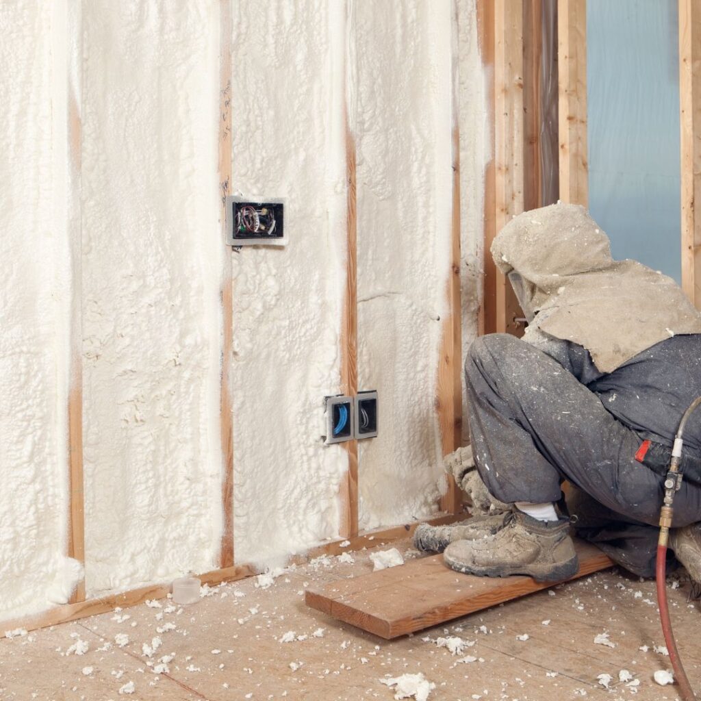 a worker spray foaming a basement wall