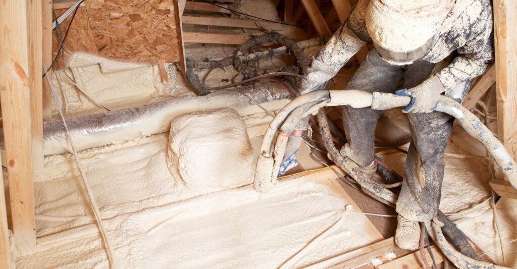 a worker spray foaming an attic