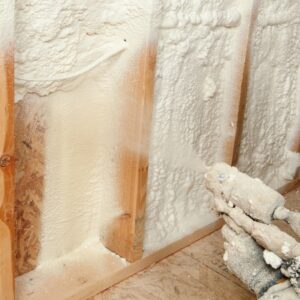 A close-up view of spray foam insulation being applied between wooden studs, expanding to create an airtight seal.