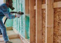 A Pro-Seal Spray Foam professional in full protective gear applies high-performance spray foam insulation to a wall cavity.
